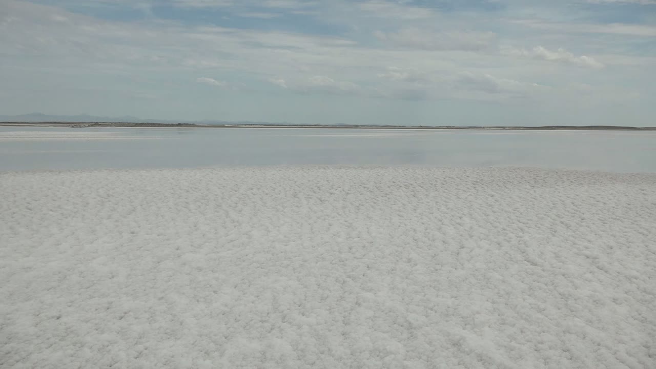 White salt flat with low horizon and soft cloud cover