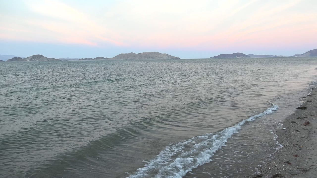 Foamy water runs diagonally along the Bahia De Los Angeles shoreline, with the beach edge on the right, rippled water to the left, and no visible people.