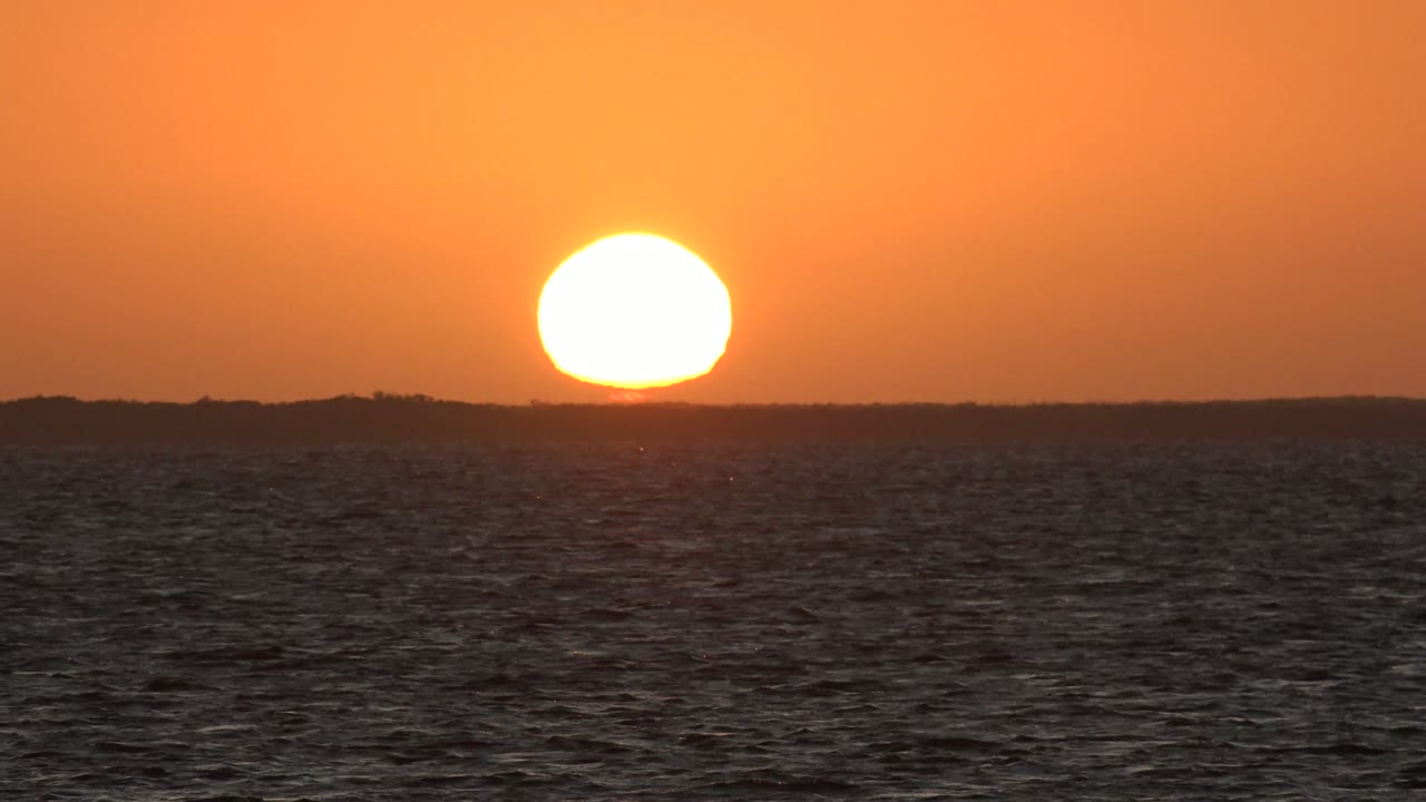 At 0:02 in San Carlos, Baja California Sur, the sun is lower over the horizon, with a black-blue ocean foreground and no visible people.
