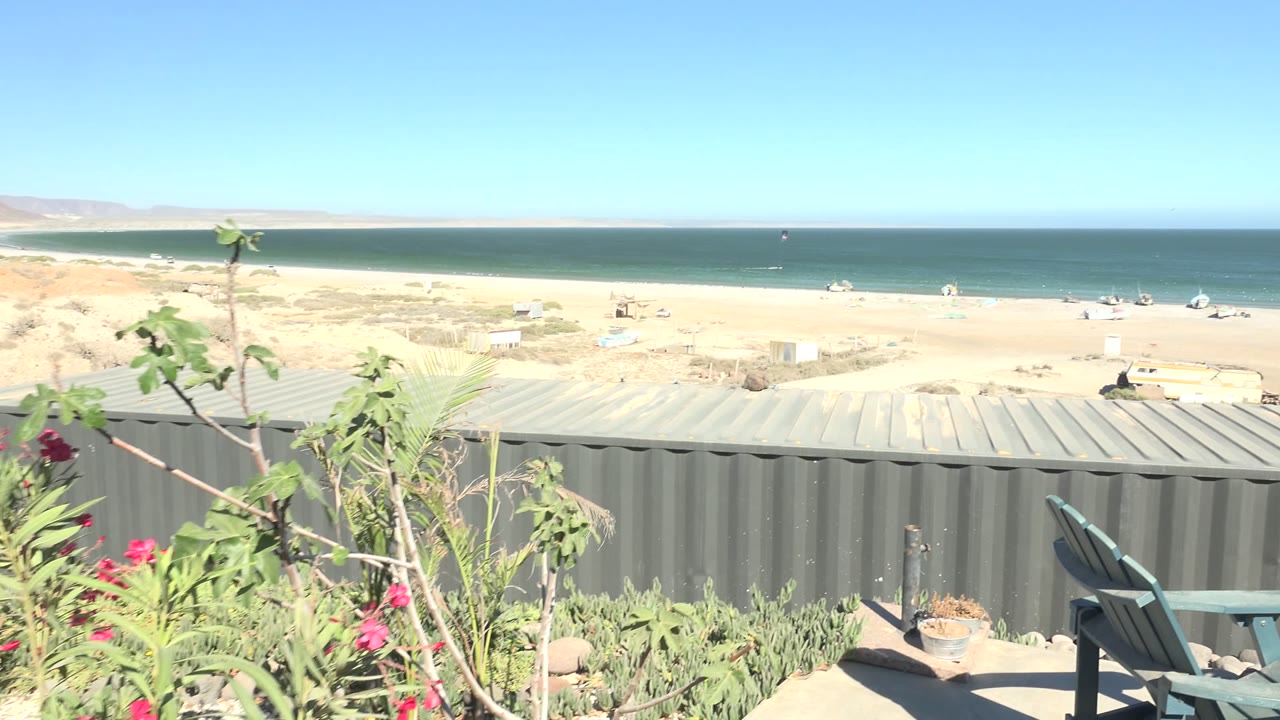 Beach and ocean horizon above gray metal structure and foreground plants.