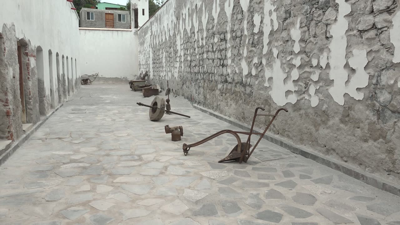 Forward view along cobblestone path beside peeling stone wall