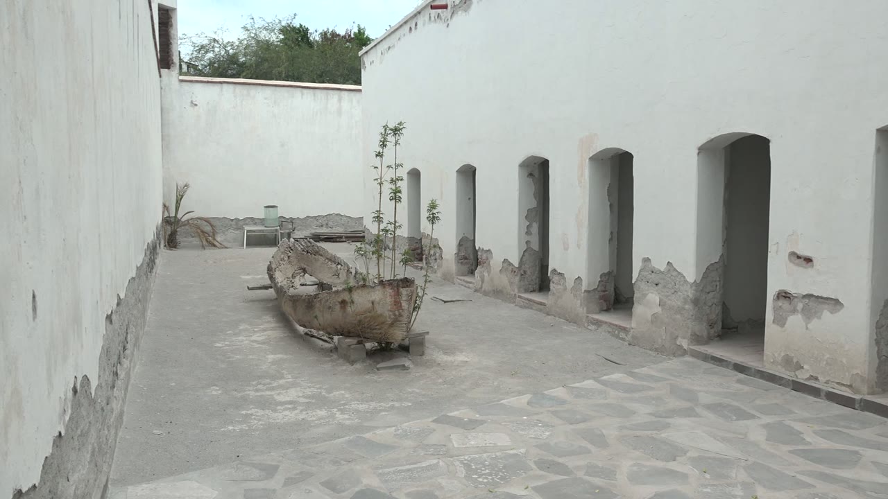 Narrow courtyard with white walls, arches, and central planter.