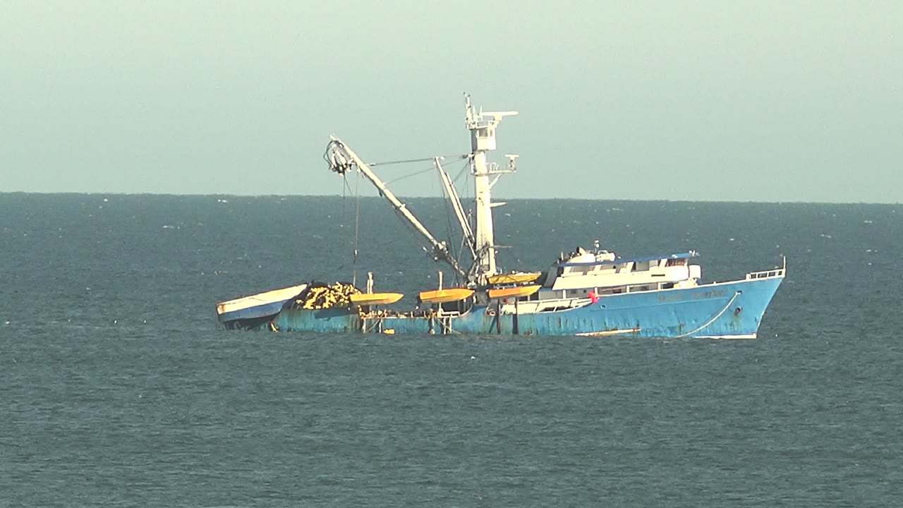 Partly submerged blue vessel with crane on calm sea