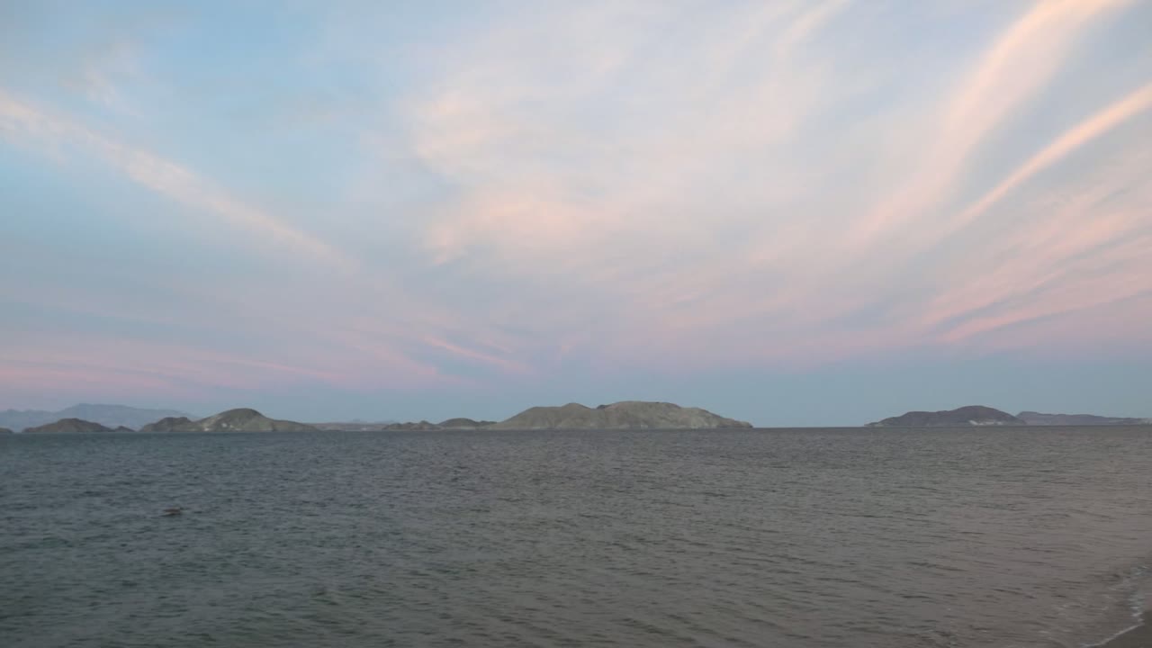 Open water and low islands beneath soft pink cloud bands