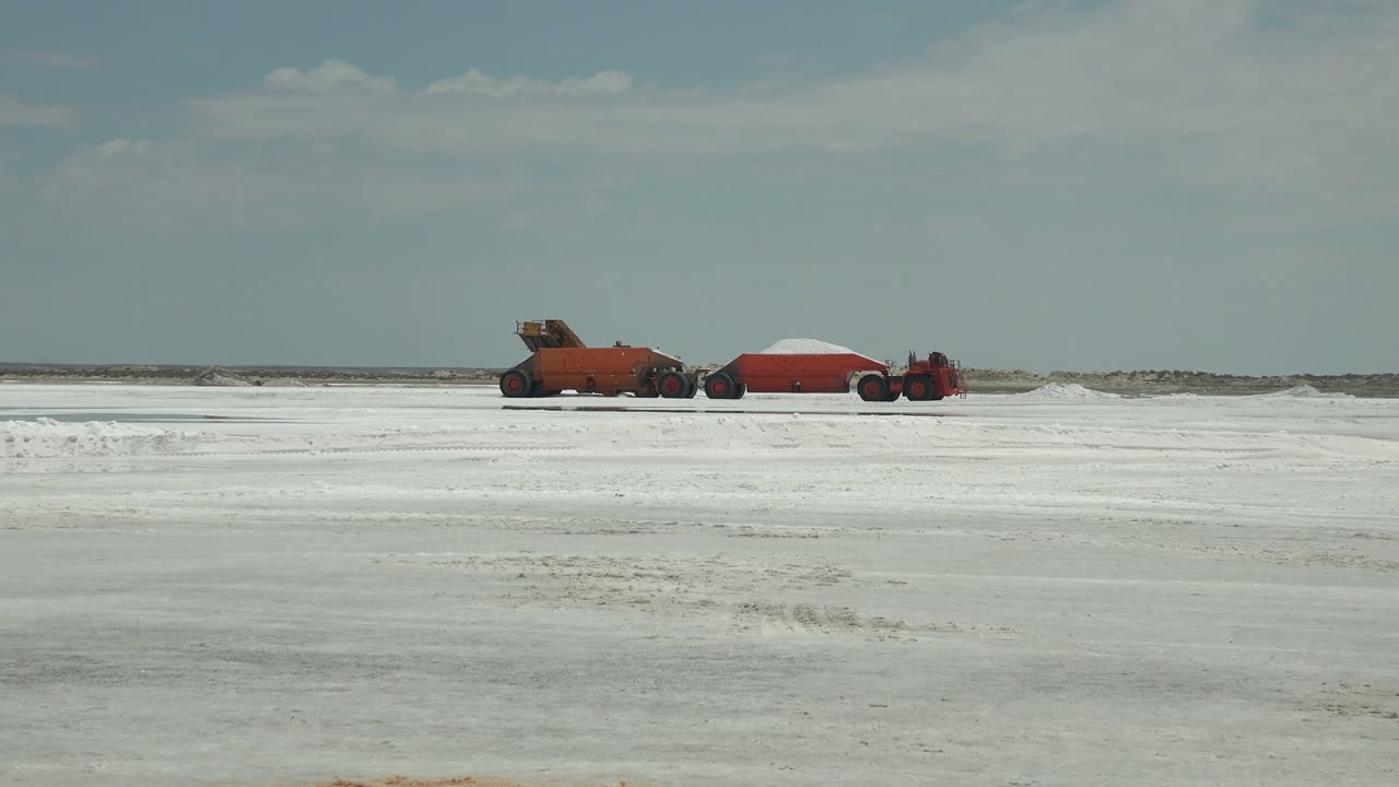 The third frame places the red machinery train farther right in the wide Guerrero Negro landscape, with white textured ground and no visible people.