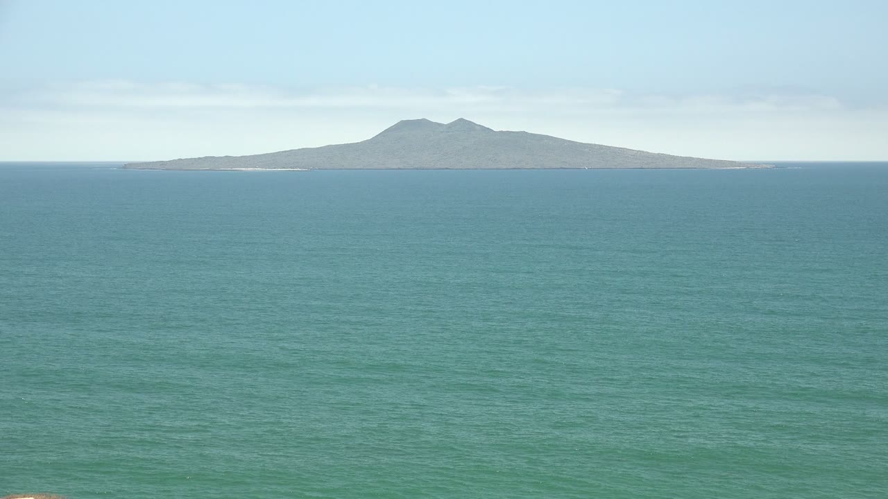 San Quintin BC Mexico ocean frame showing the island slightly right of center, a wide band of textured water, soft haze near the horizon, and no visible people.