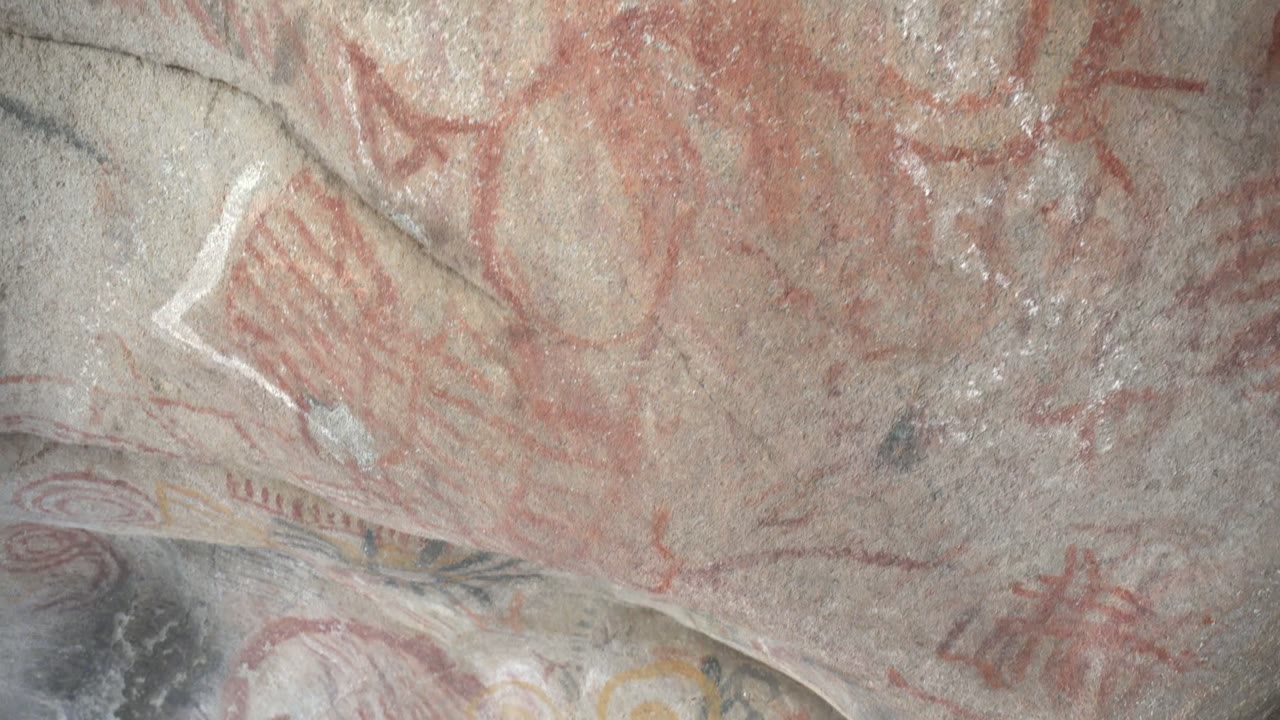 Red handprint shapes and circular designs remain visible across the gray stone face in Santa Rosalia, Baja California Sur, with no visible people.
