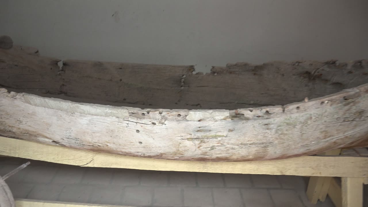 Old boat hull with dark upper planks and pale lower side.