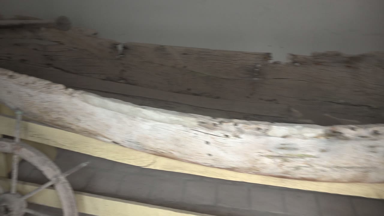 A curved section of the weathered boat fills the frame in Mulege, with part of a ship's wheel visible near the lower left and no visible people.