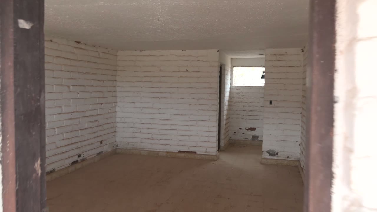 At 0:00 in Mulege, Baja California Sur, Mexico, the camera looks through dark doorway edges into an empty white brick room with a concrete floor, a small high window, and no visible people.