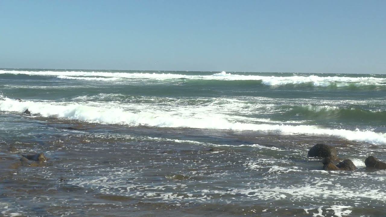 Foamy wave lines moving across a rocky ocean shoreline