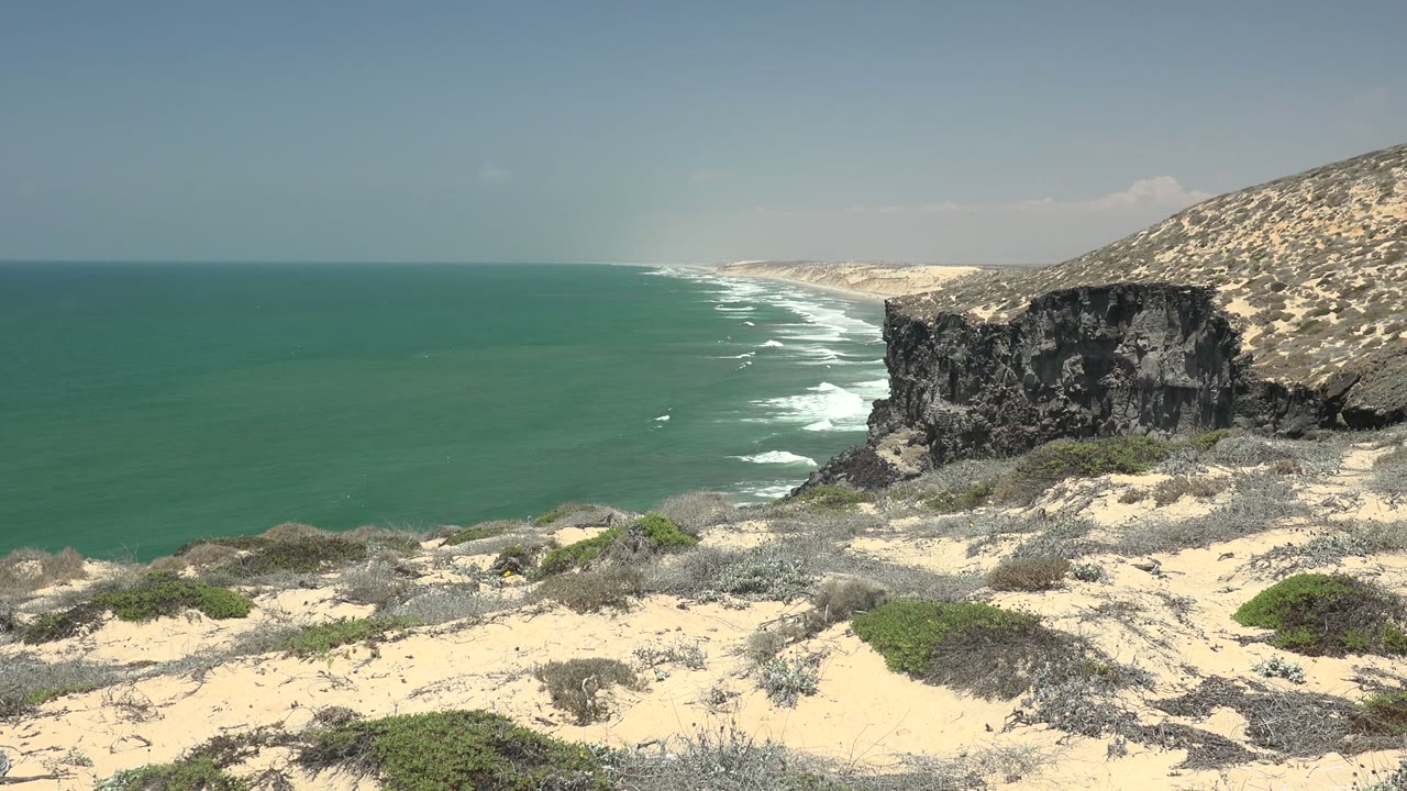 Coastal cliff above turquoise water with surf lines