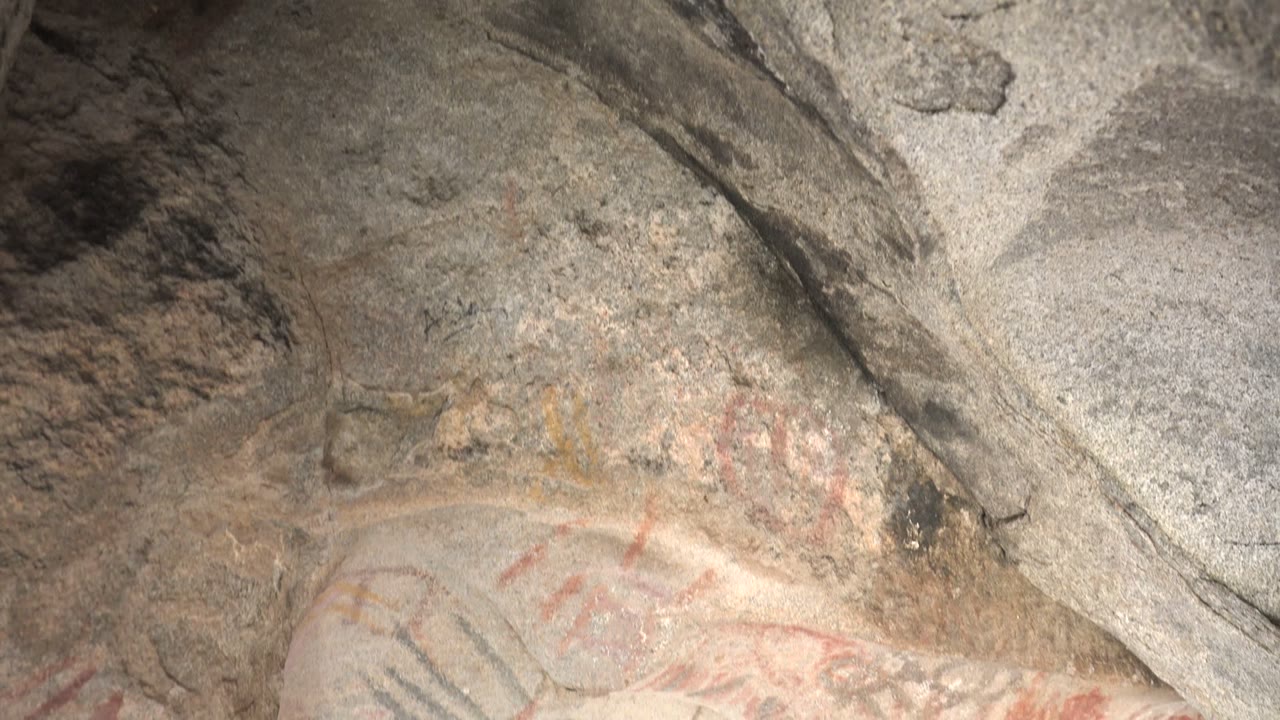 Close view of faded red and black pigment marks on a weathered stone surface in Santa Rosalia, Baja California Sur, Mexico, with no visible people.
