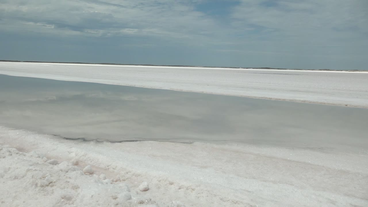 Opening frame of a white shore and pale frozen-looking water in Guerrero Negro, Baja California Sur, with low clouds and no visible people.
