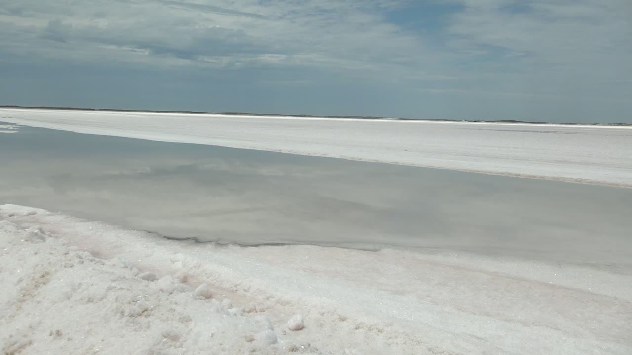 Low view of white bank curving along gray-blue water.