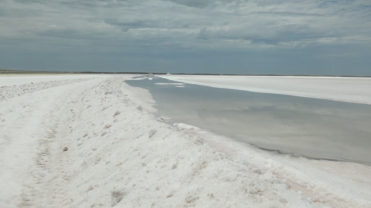 Snow-covered path and frozen water with a low horizon.