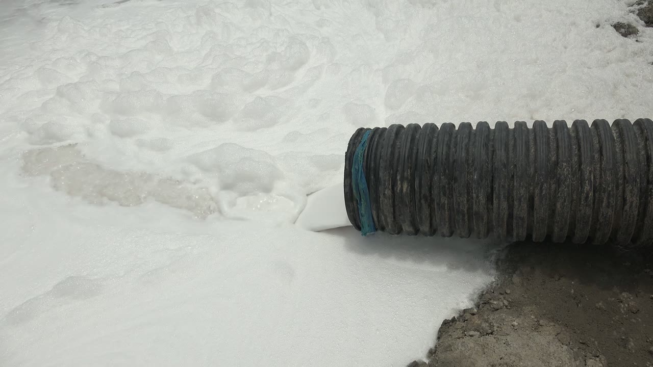 Blue-rimmed black hose on foamy white ground