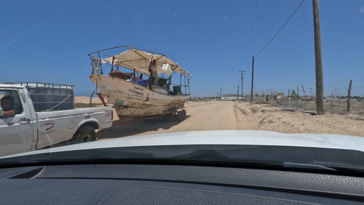 Pickup cab and towed boat passing close to the windshield view.