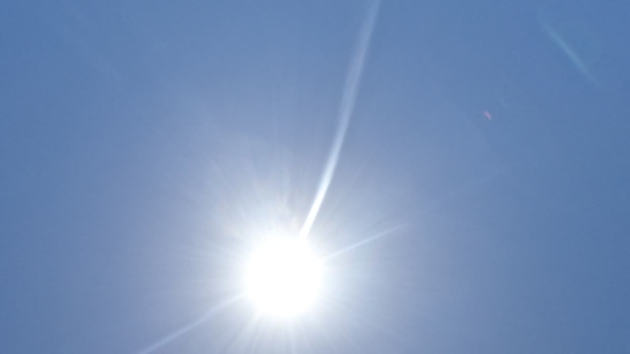 Bright sun and lens flare fill a clear blue sky in Baja California, Mexico, with no beach surface visible yet.