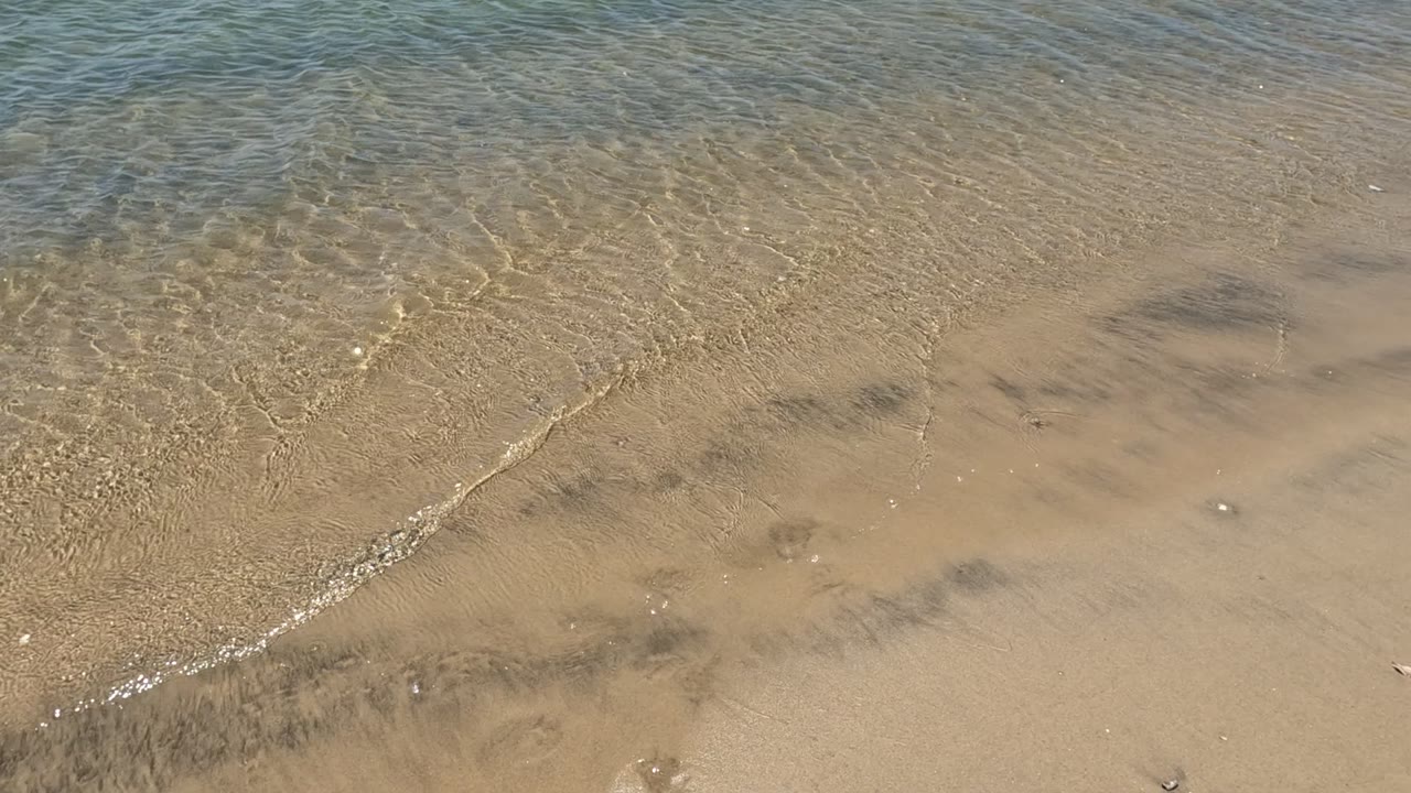 Thin wave edge crossing wet sand