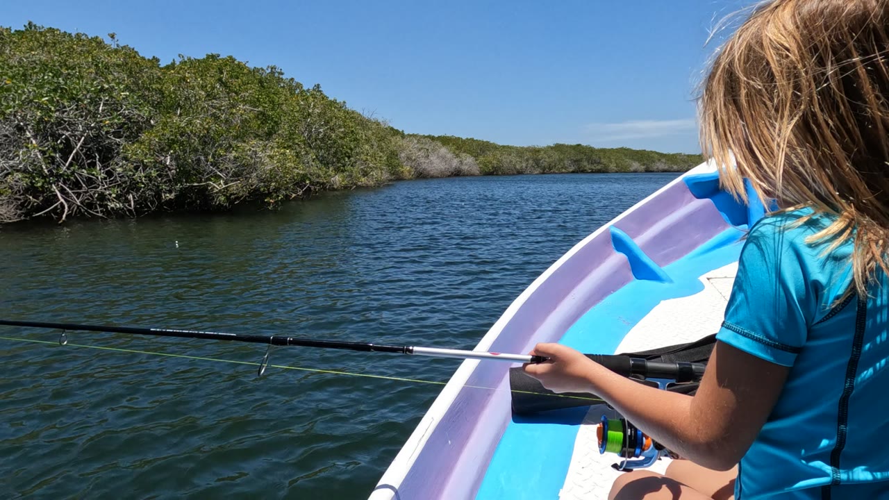 Girl leaning forward with fishing rod extended across the boat bow.