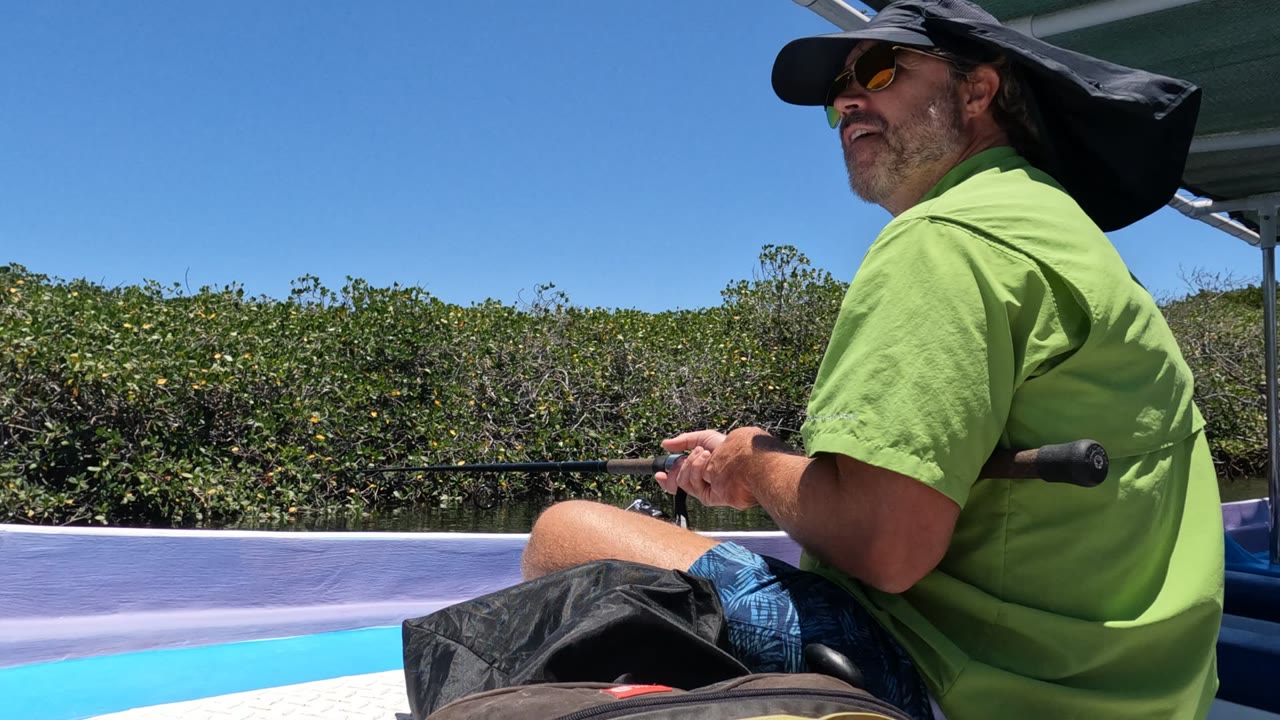 Seated fisherman holding a rod under clear blue sky