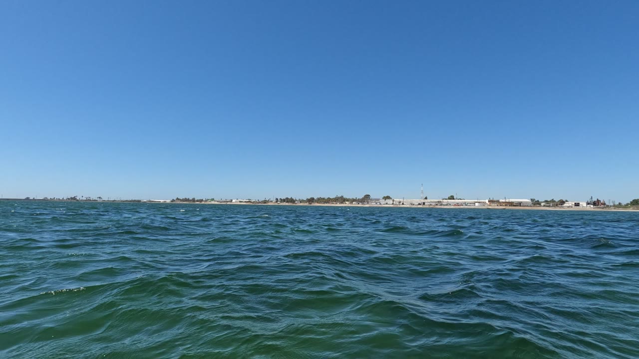 Opening frame from Baja California, Mexico showing blue-green ocean water, a low distant shoreline, clear sky, and no visible people.