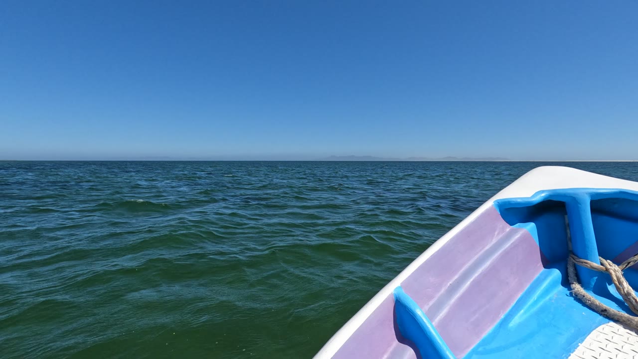 Boat bow and rope angled toward rippled ocean horizon.