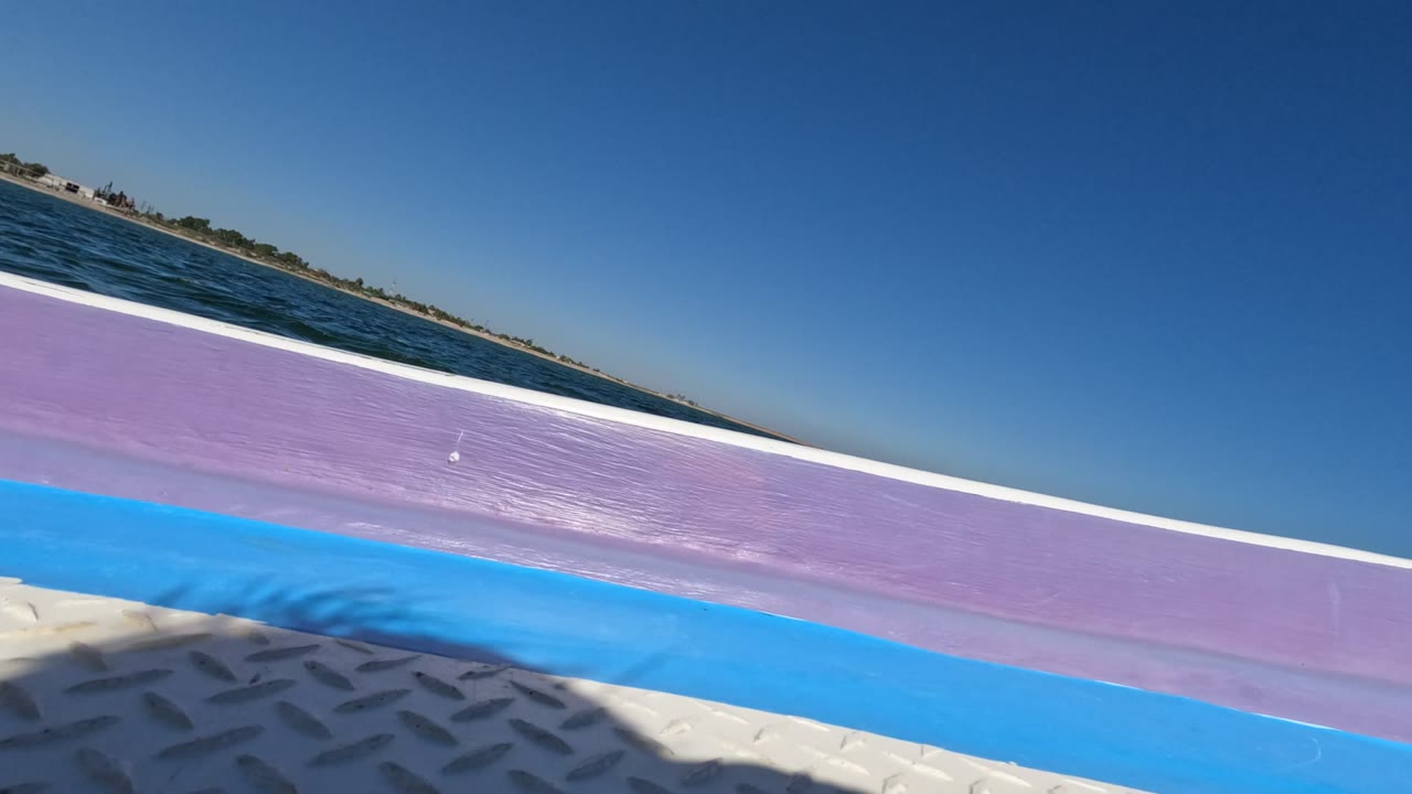 Tilted boat rail and ocean horizon under blue sky.