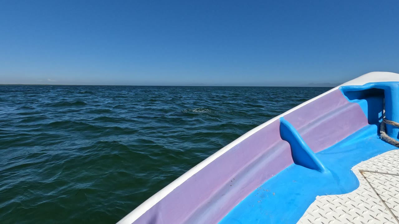 Boat deck foreground with rippled ocean and clear horizon