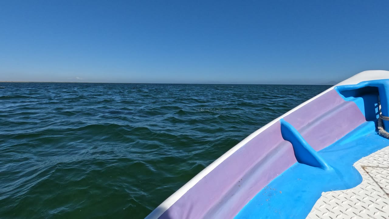 The right side of the boat bow remains prominent as darker wave texture crosses the open sea in Baja California, Mexico, with no visible people.