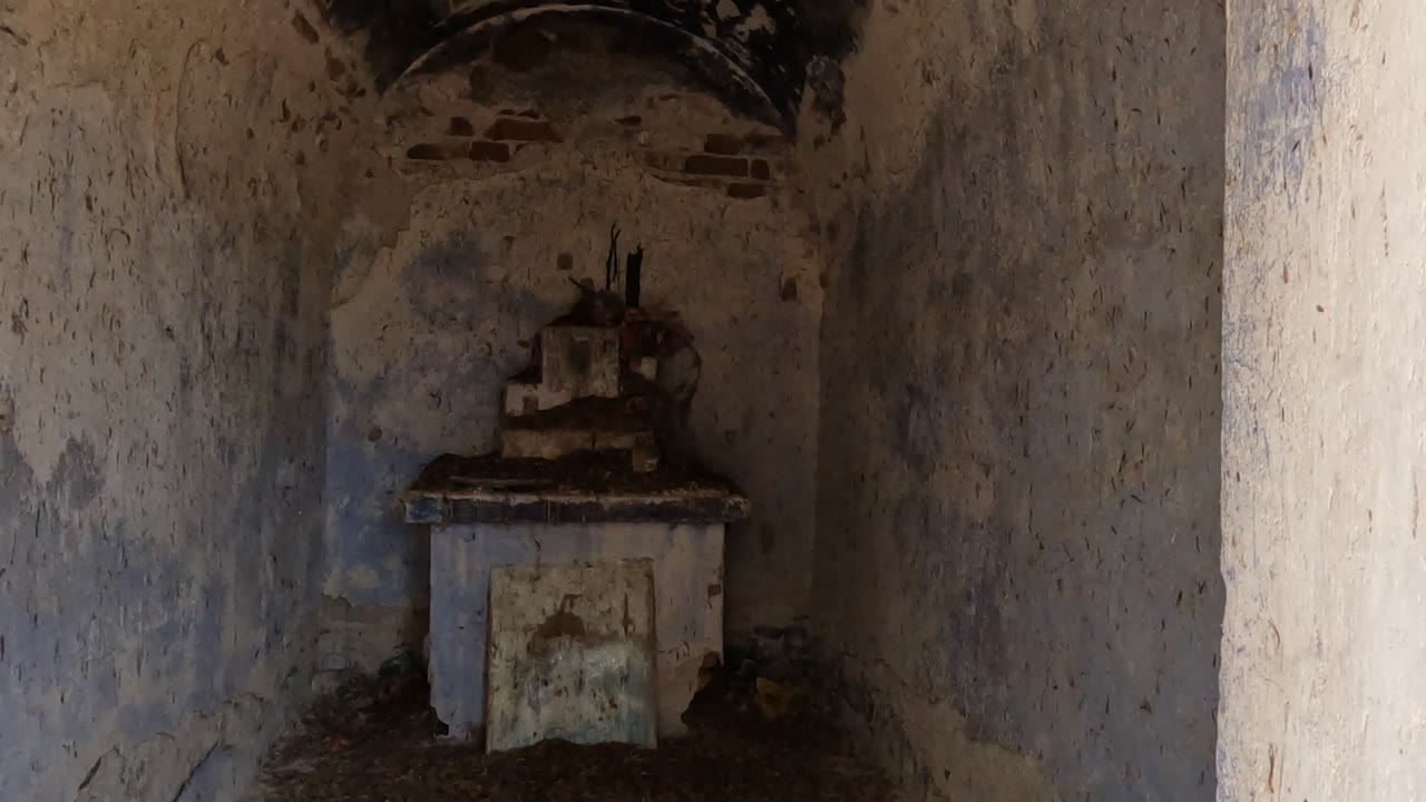 Weathered interior wall and small altar-like feature in shadow.