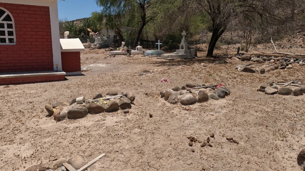 Dry cemetery ground with chapel edge, stone graves, and crosses