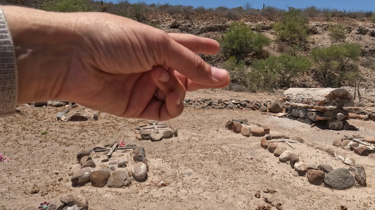 Hand pointing over stone arrangements in a dry rocky landscape