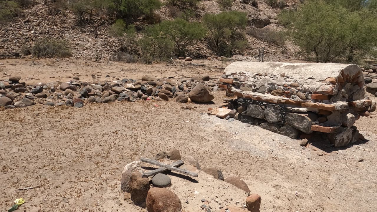 Stone and brick oven in sandy terrain with rocks and trees behind it