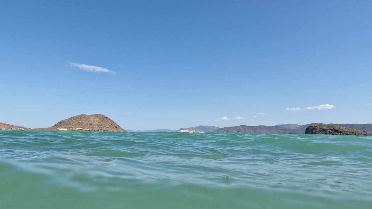 Rolling green-blue wave with rocky island beyond
