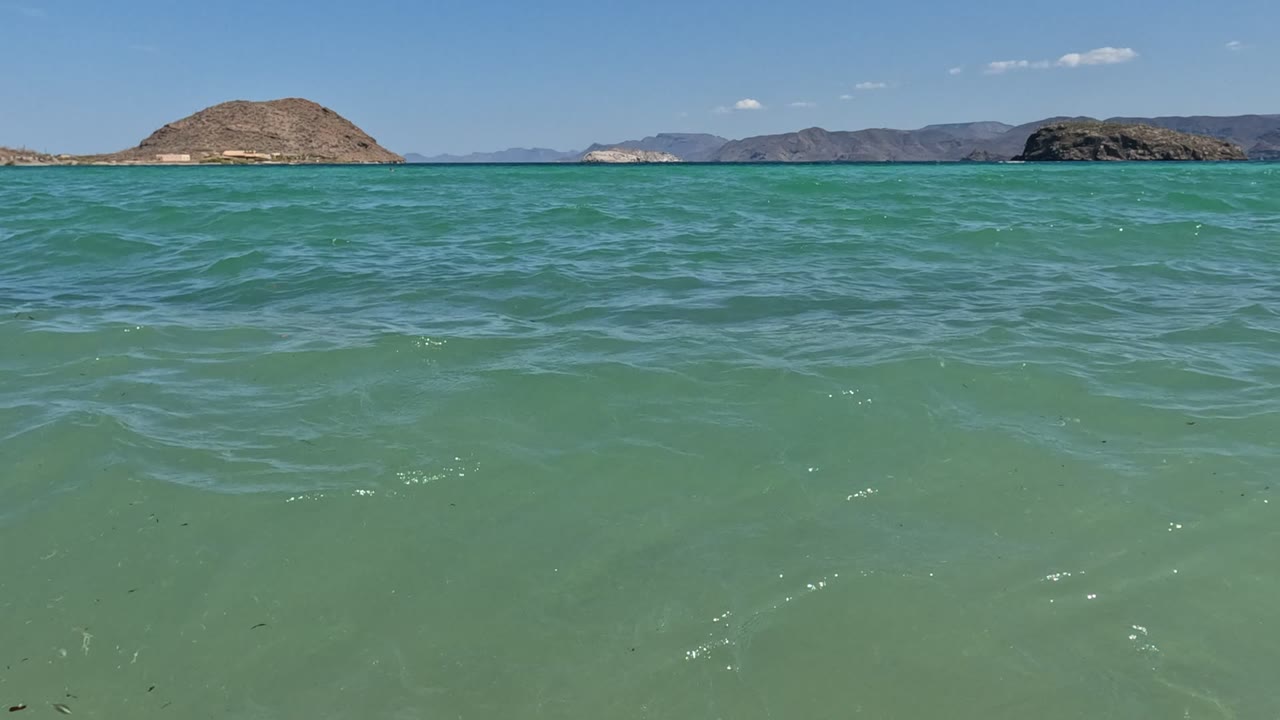 Green ocean surface with low islands and hills beyond the horizon.