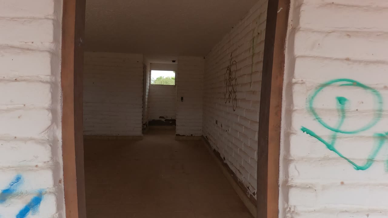 A closer moment on the Baja California interior wall shows green graffiti across white brick with blue spray paint low in frame and no visible people.