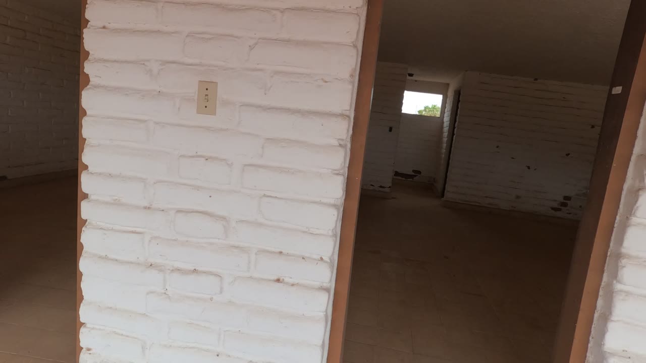 White brick wall with a light switch and green graffiti near a doorway.