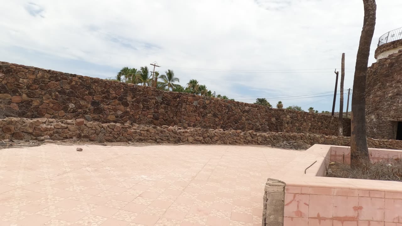 Empty stone courtyard with circular tower and low pink wall