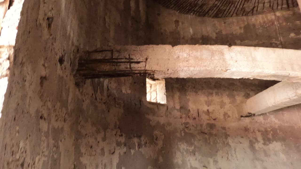 Concrete wall and beam with a small window in dim light.