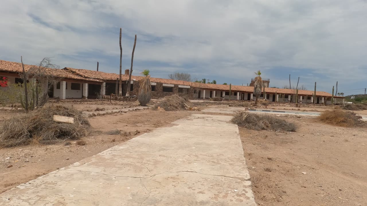 Dry desert courtyard with path and red-roofed building
