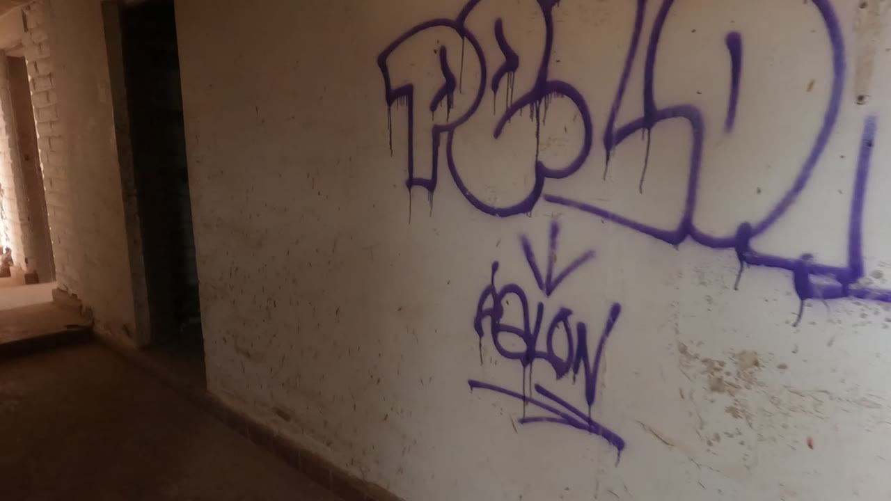 Graffiti wall with a doorway and bright window light at the edge.