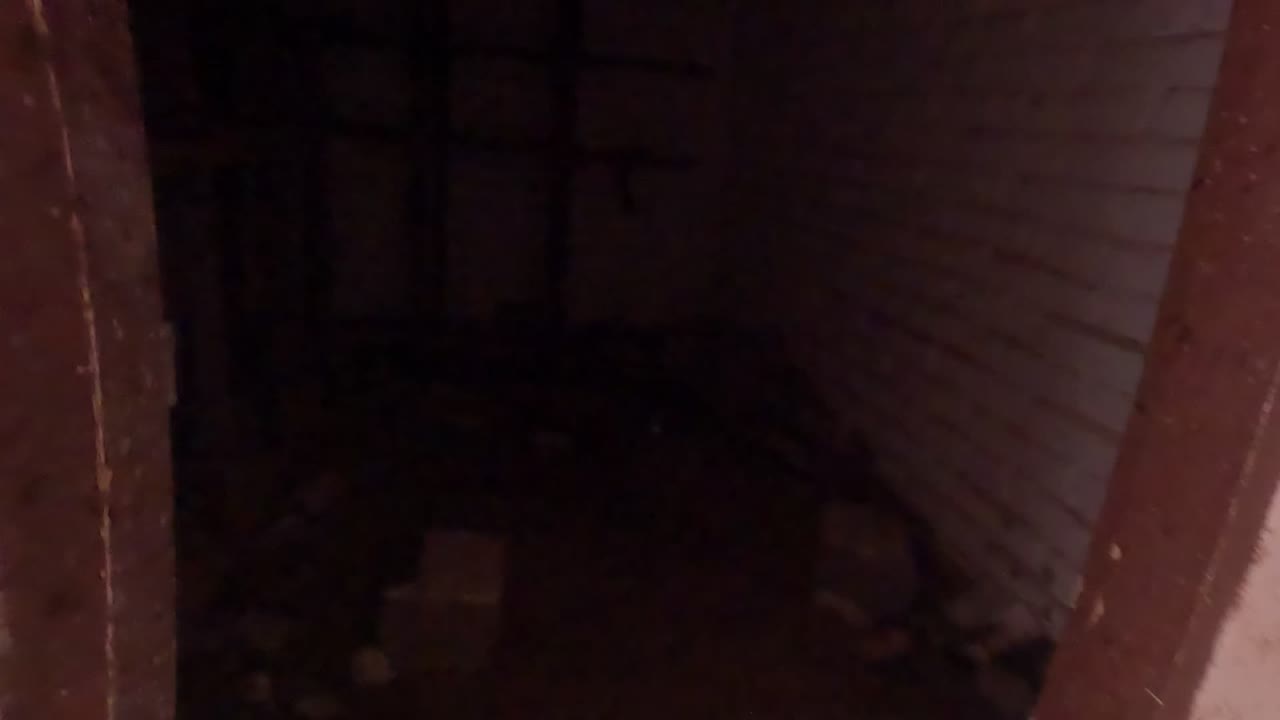 A dark debris-filled interior opens toward a brighter white brick doorway in Baja California, Mexico, with no visible people.