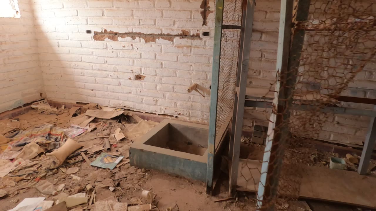 Baja California, Mexico interior with white brick walls, scattered debris, a concrete sink, a metal frame, and a partially visible person at the right edge.