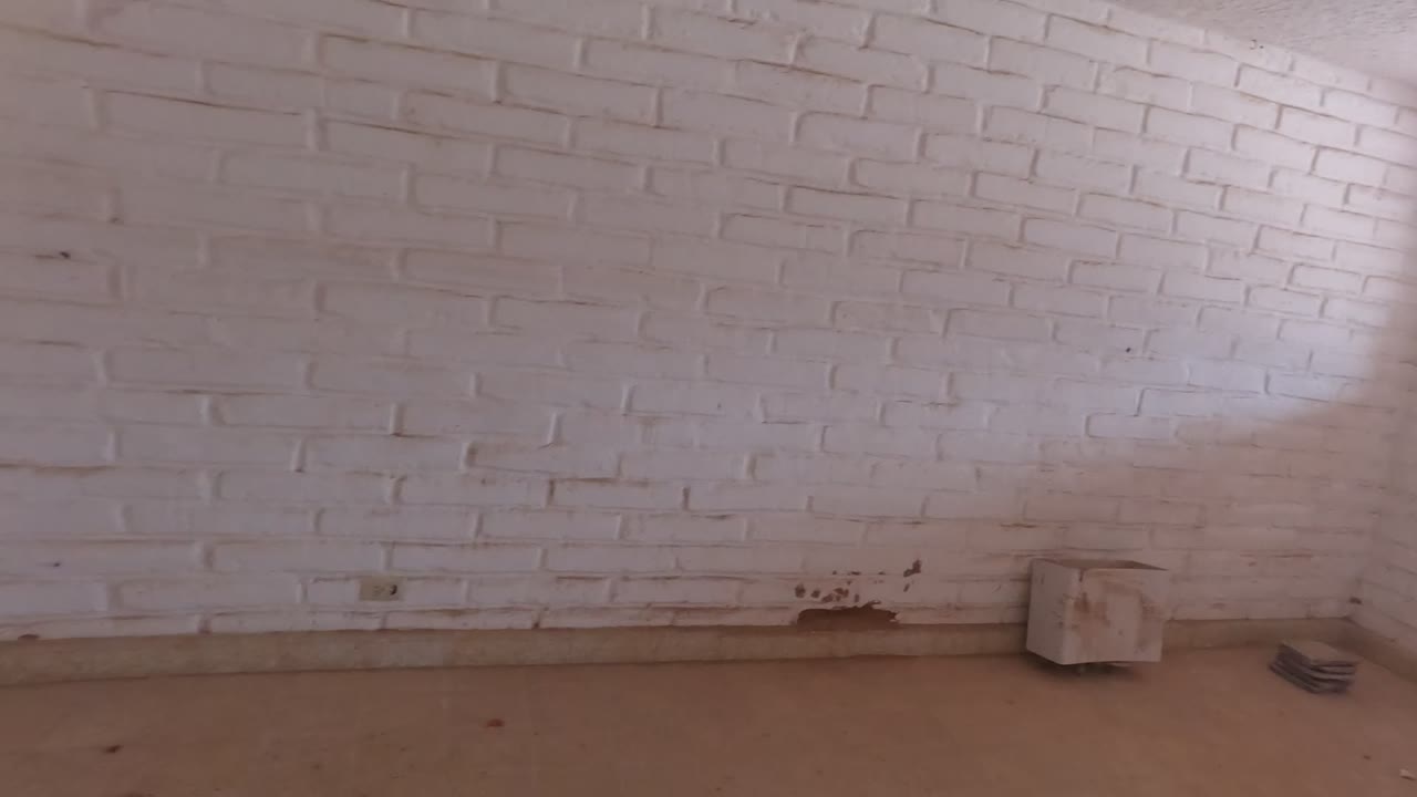 Empty unfinished room in Mulege, Baja California Mexico with white brick walls, beige tile floor, low wall marks, and no visible people.