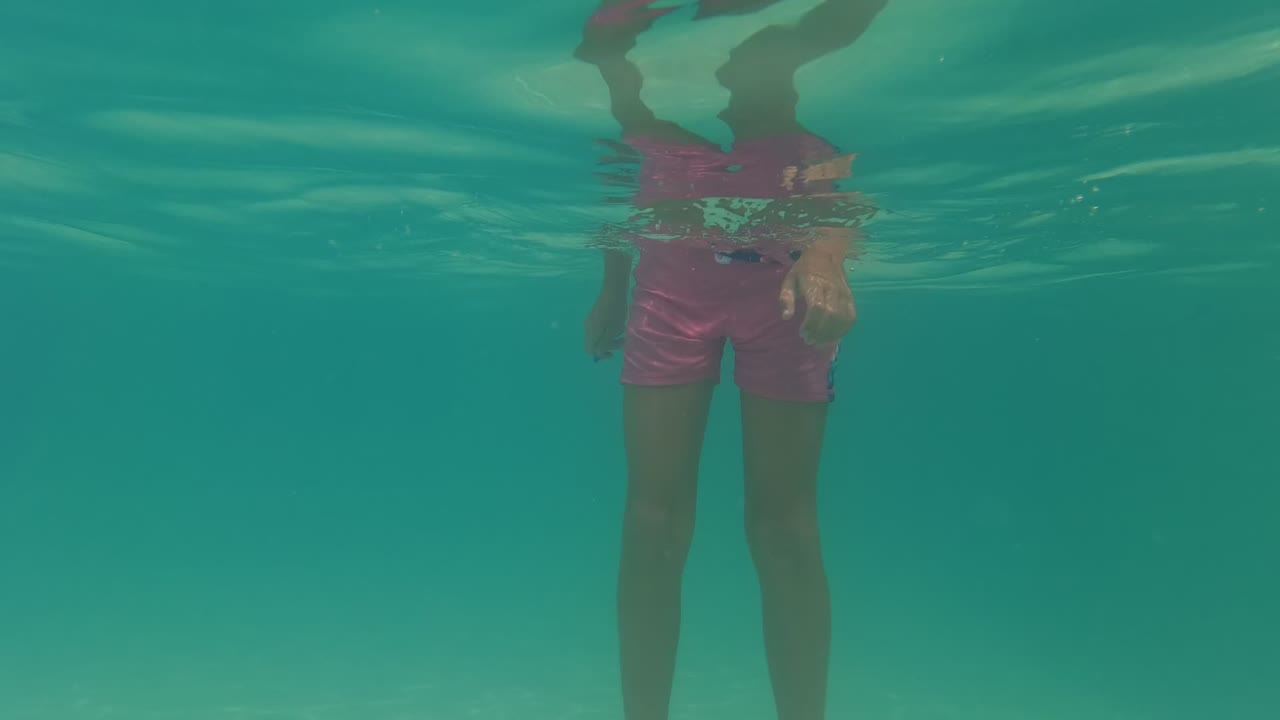 Underwater view of a girl standing with her lower body visible below the pool surface.