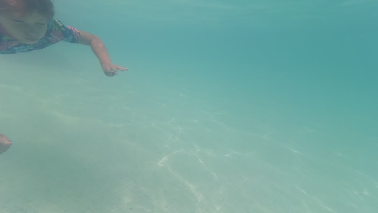 Child swimming underwater near the top of the frame.