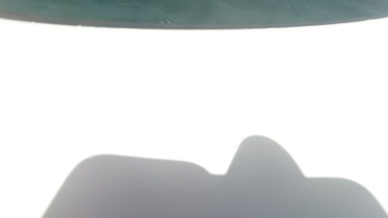 A bright overexposed section of the white boat and a partial passenger leg appear near the waterline in Baja California, Mexico.