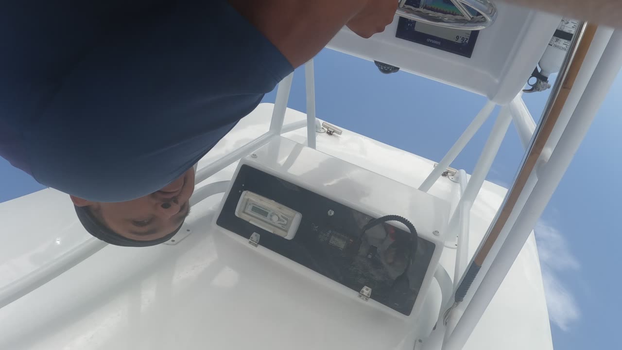 In Baja California, Mexico, the man's face is partly visible near the upper edge as the tilted view shows the black control panel, steering wheel, white deck surfaces, and clear blue sky.